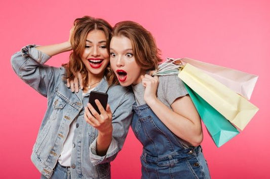 Two friends, one of them hoding a mobile phone and the other one holding shopping bags, were shocked by something she was watching via phone.