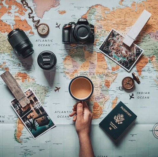 a man hand, passport a camera and a coffee mug and a map